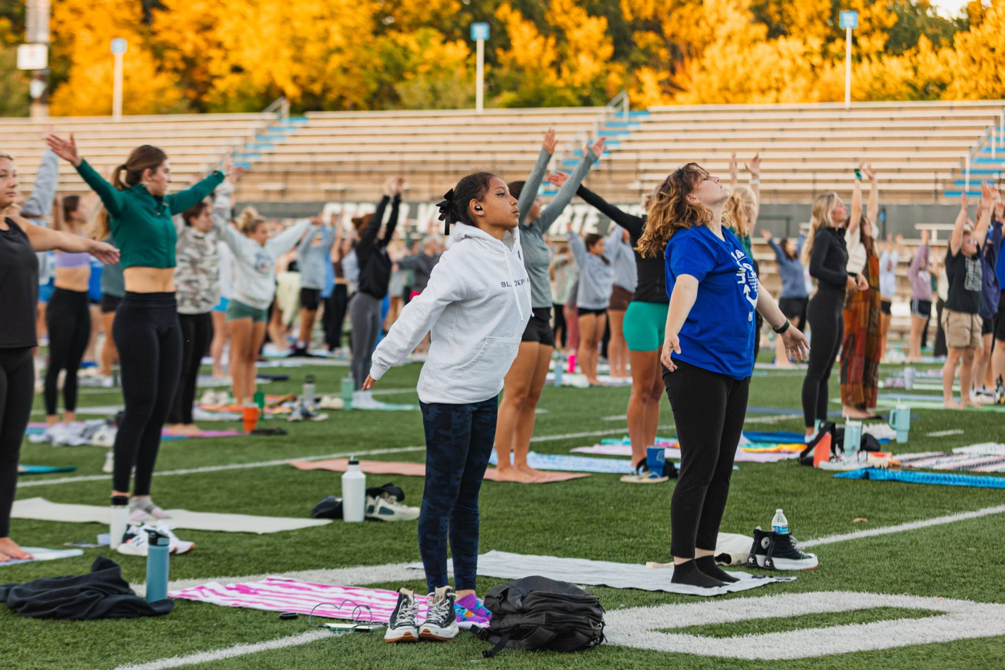 students take a yoga class on the football field.